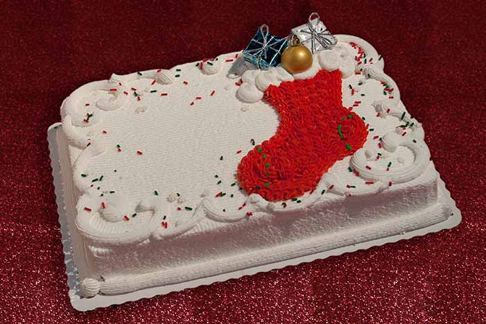 Luxury Christmas cake with snowflake decorations on two tiered iced layers  with a silver doilie and slice on a plate with winter holly Stock Photo -  Alamy